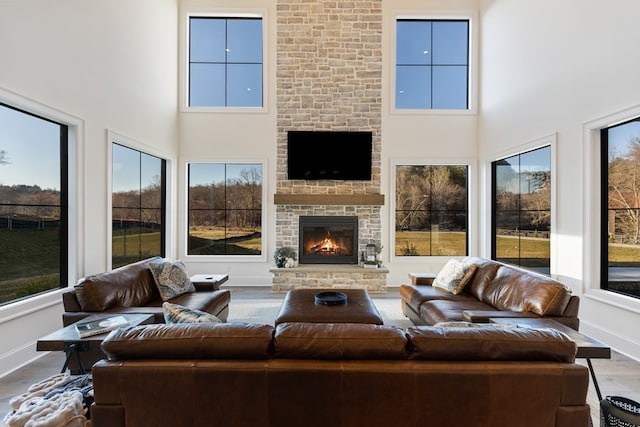 living area featuring plenty of natural light, a large fireplace, baseboards, and wood finished floors