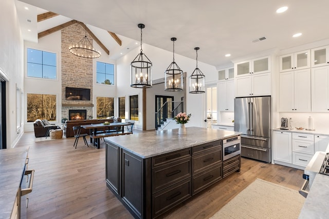 kitchen with built in microwave, a fireplace, an inviting chandelier, wood finished floors, and high end fridge