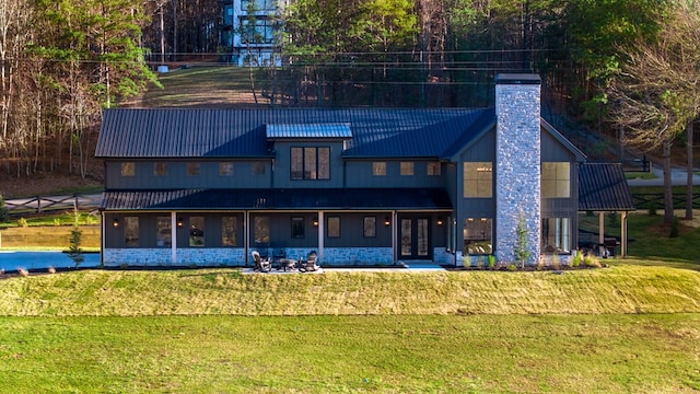 rear view of property with metal roof, a lawn, a chimney, and french doors