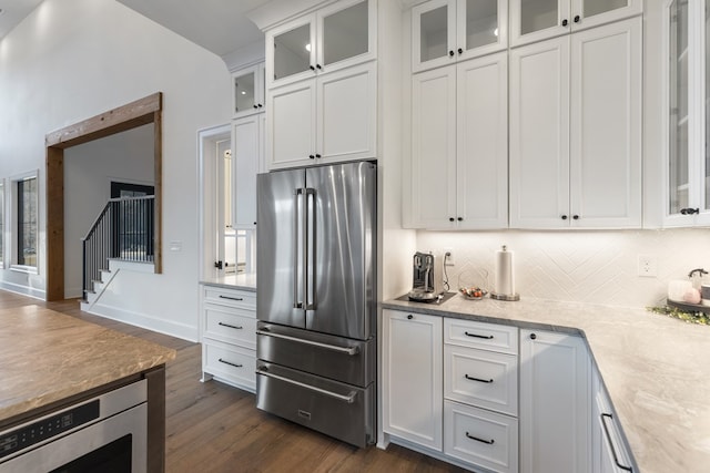 kitchen with dark wood-style floors, backsplash, appliances with stainless steel finishes, and white cabinets