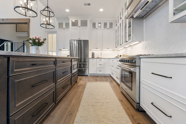 kitchen featuring visible vents, an inviting chandelier, extractor fan, white cabinets, and high quality appliances