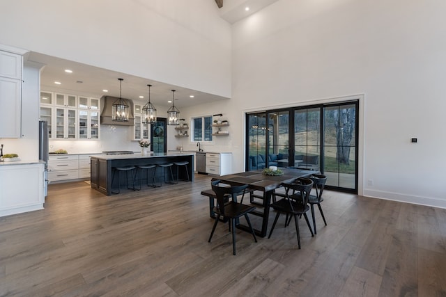 dining room with baseboards, dark wood finished floors, a chandelier, recessed lighting, and a high ceiling