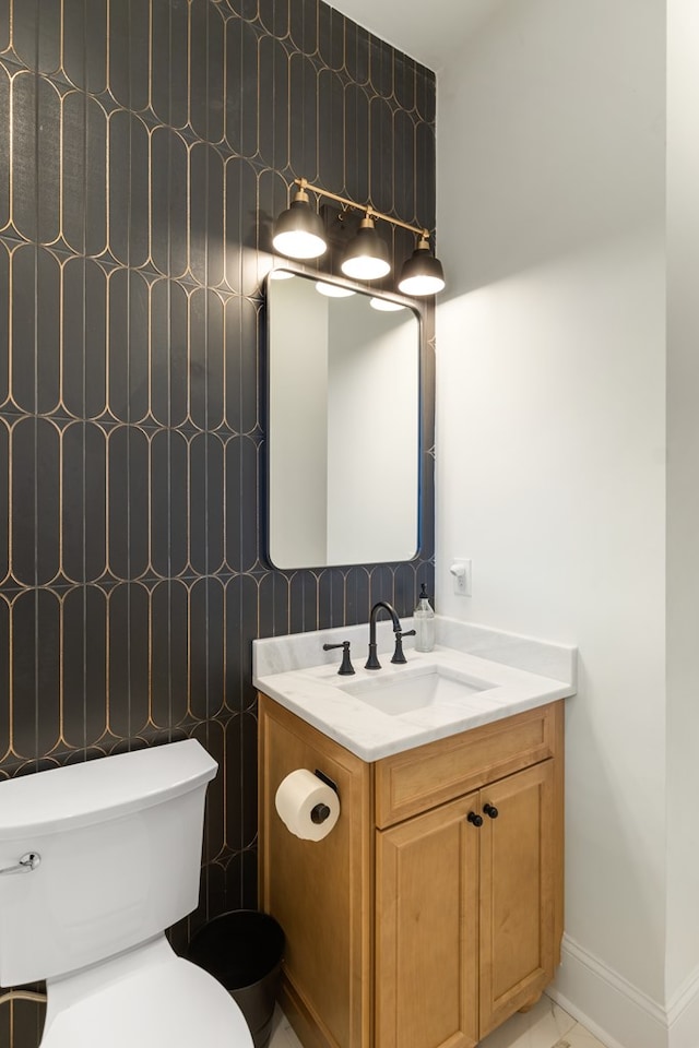 bathroom featuring vanity, toilet, baseboards, and marble finish floor