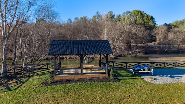 view of community featuring a lawn, a water view, and fence