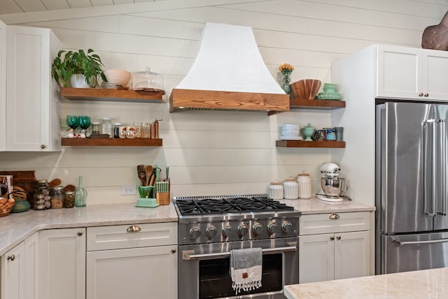 kitchen with appliances with stainless steel finishes, white cabinets, and custom range hood