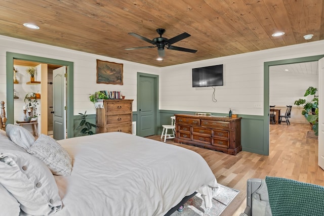 bedroom featuring wooden walls, light hardwood / wood-style flooring, wood ceiling, and ceiling fan