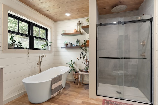 bathroom with wood walls, hardwood / wood-style flooring, and plus walk in shower