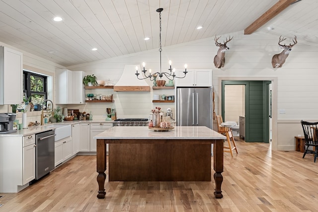 kitchen with a center island, appliances with stainless steel finishes, vaulted ceiling with beams, and light wood-type flooring