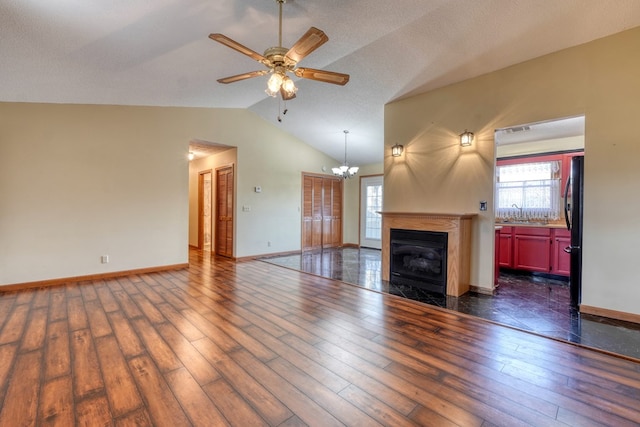 unfurnished living room with ceiling fan with notable chandelier, dark hardwood / wood-style floors, a textured ceiling, and lofted ceiling