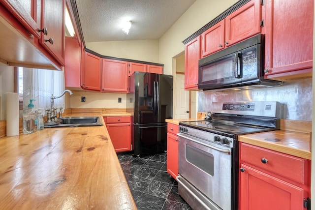 kitchen featuring lofted ceiling, butcher block countertops, black appliances, and sink