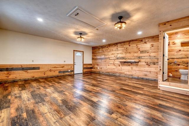 spare room with dark hardwood / wood-style flooring, a textured ceiling, and wooden walls