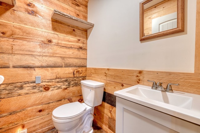 bathroom featuring vanity, toilet, and wooden walls