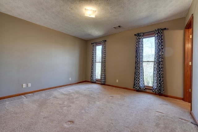 spare room with a textured ceiling and light carpet