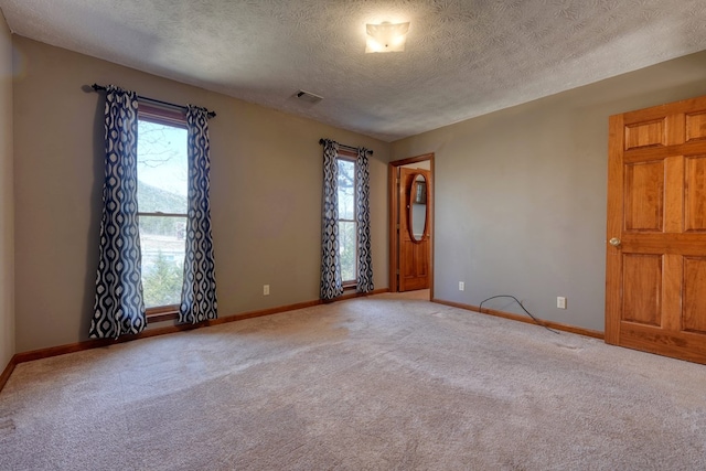 carpeted empty room featuring a textured ceiling