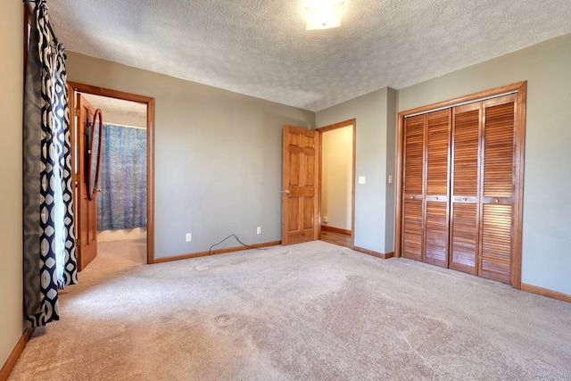 unfurnished bedroom featuring a textured ceiling, a closet, connected bathroom, and light colored carpet