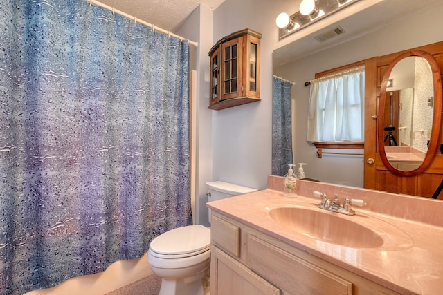 bathroom featuring a textured ceiling, toilet, and vanity