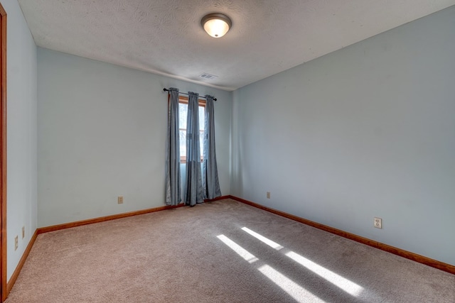 empty room with light carpet and a textured ceiling