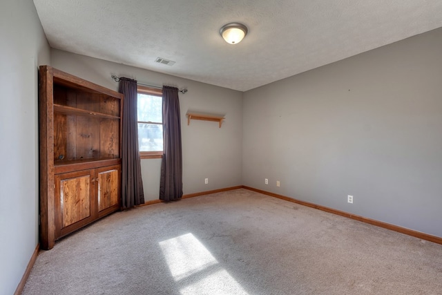 unfurnished room with a textured ceiling and light colored carpet