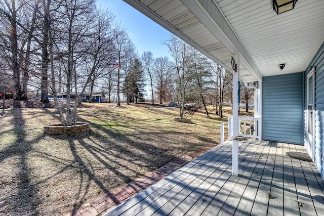 wooden terrace featuring a lawn and a porch