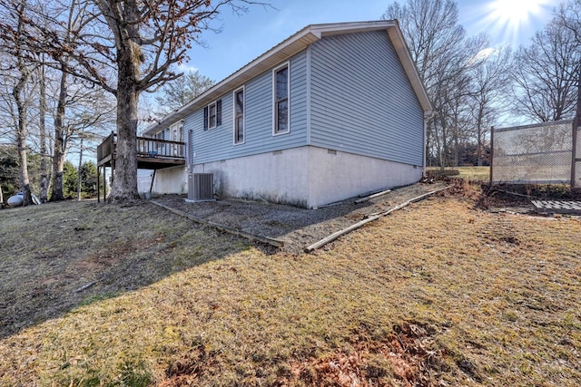 view of property exterior with central AC, a wooden deck, and a lawn