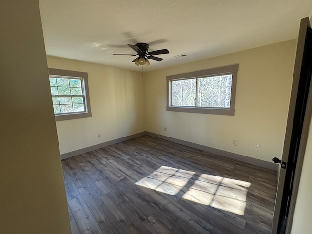 empty room featuring dark hardwood / wood-style floors, a wealth of natural light, and ceiling fan