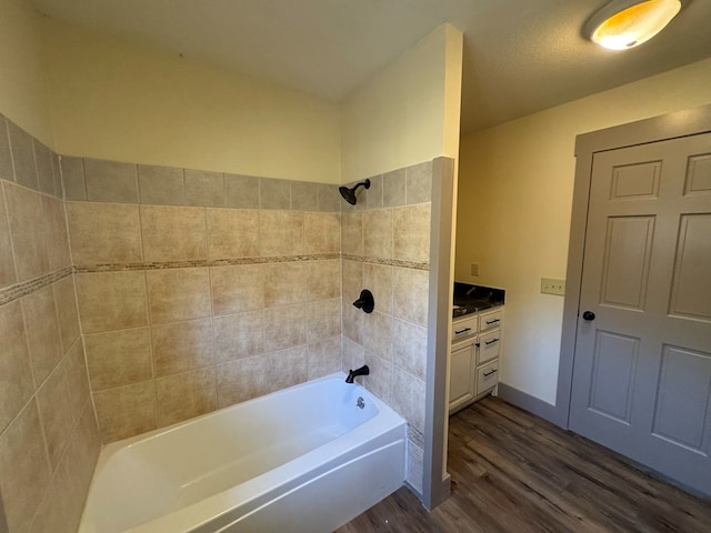 bathroom with hardwood / wood-style floors, vanity, and tiled shower / bath combo