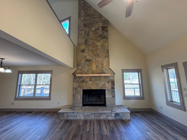 unfurnished living room featuring a fireplace, wood-type flooring, ceiling fan with notable chandelier, and high vaulted ceiling