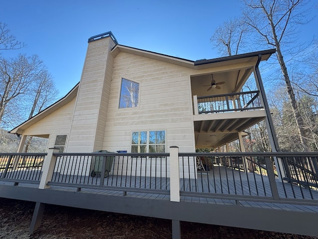 back of property with ceiling fan, a balcony, and a deck