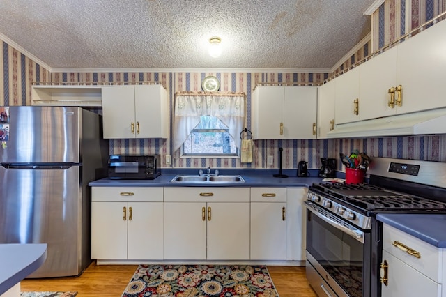 kitchen featuring sink, appliances with stainless steel finishes, ornamental molding, a textured ceiling, and white cabinets