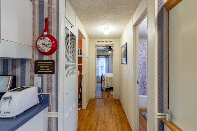 hallway with light hardwood / wood-style floors and a textured ceiling