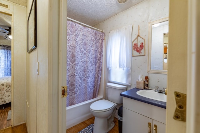 full bathroom with vanity, wood-type flooring, shower / bath combination with curtain, a textured ceiling, and toilet