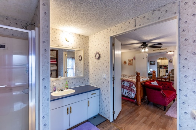 bathroom with vanity, hardwood / wood-style floors, a shower with door, and a textured ceiling