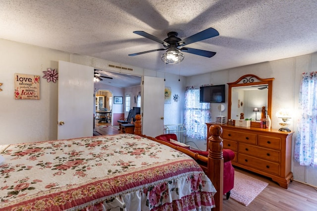 bedroom with ceiling fan, wood-type flooring, and a textured ceiling