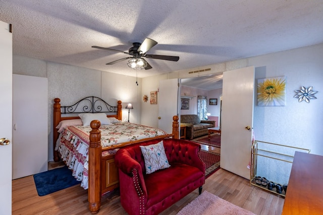 bedroom with ceiling fan, hardwood / wood-style floors, and a textured ceiling