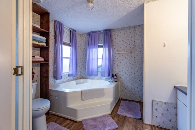 bathroom featuring toilet, wood-type flooring, a textured ceiling, vanity, and a bathtub