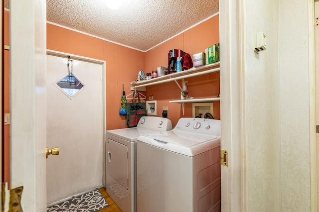 laundry area with a textured ceiling, wood-type flooring, and washing machine and clothes dryer