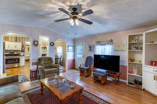 living room featuring ceiling fan, vaulted ceiling, light hardwood / wood-style floors, and a textured ceiling