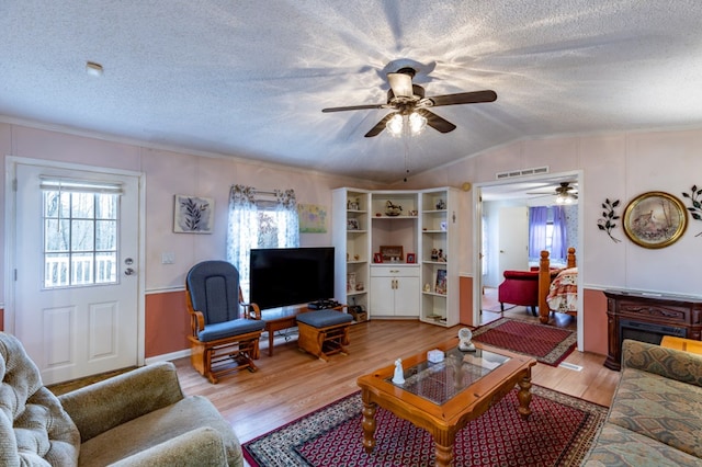 living room with lofted ceiling, a wealth of natural light, light hardwood / wood-style floors, and a textured ceiling