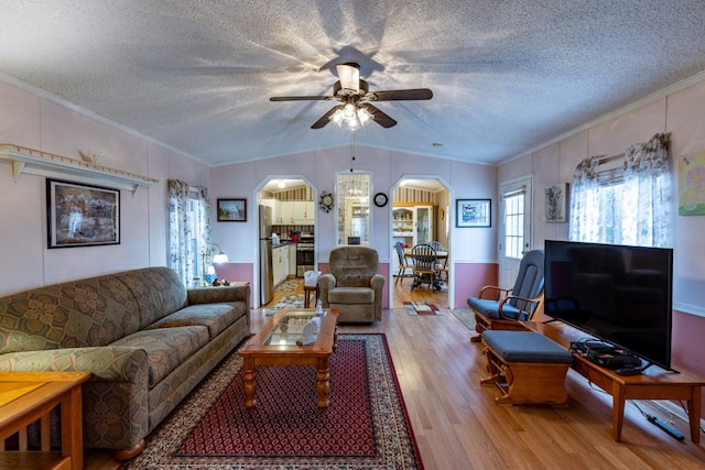 living room with crown molding, lofted ceiling, a textured ceiling, and light hardwood / wood-style flooring