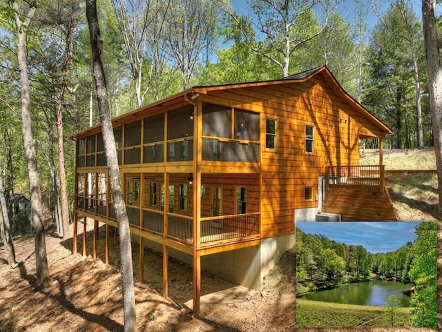 rear view of property featuring a sunroom and a deck with water view