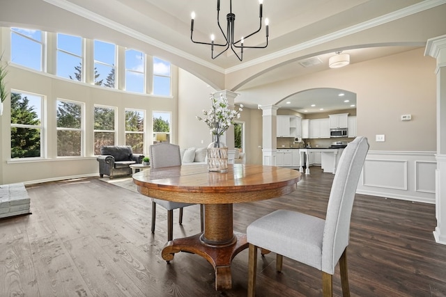 6665 Flagstone Ct, Cumming, GA 30028 - dining room with dark wood finished floors, decorative columns, a chandelier, ornamental molding, and arched walkways