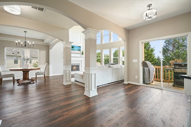 6665 Flagstone Ct, Cumming, GA 30028 - living room with dark wood-style floors, a lit fireplace, decorative columns, a chandelier, and arched walkways
