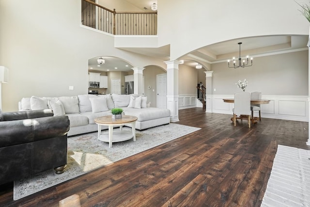 6665 Flagstone Ct, Cumming, GA 30028 - living area with arched walkways, decorative columns, dark wood-style floors, a decorative wall, and a chandelier