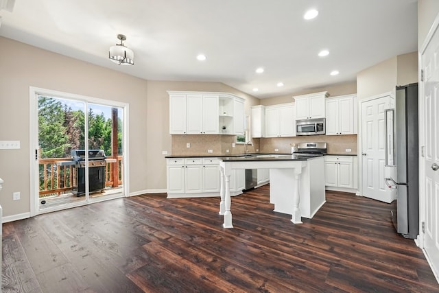 6665 Flagstone Ct, Cumming, GA 30028 - kitchen with stainless steel appliances, dark countertops, white cabinets, dark wood-type flooring, and backsplash