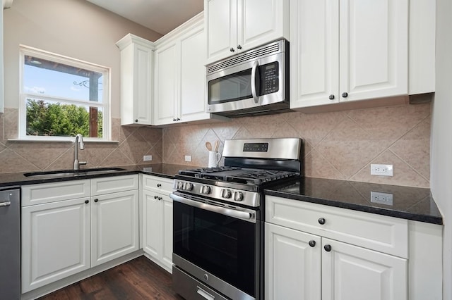 6665 Flagstone Ct, Cumming, GA 30028 - kitchen featuring appliances with stainless steel finishes, dark countertops, white cabinetry, and backsplash