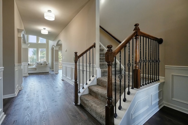 6665 Flagstone Ct, Cumming, GA 30028 - staircase with arched walkways, wood finished floors, wainscoting, a decorative wall, and lofted ceiling