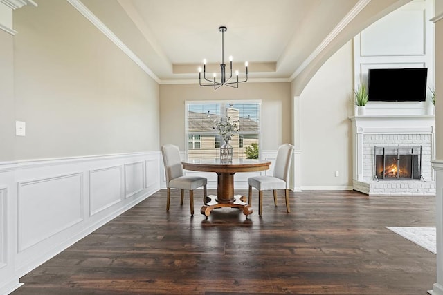 6665 Flagstone Ct, Cumming, GA 30028 - dining space featuring a chandelier, a decorative wall, dark wood-style floors, a raised ceiling, and a fireplace