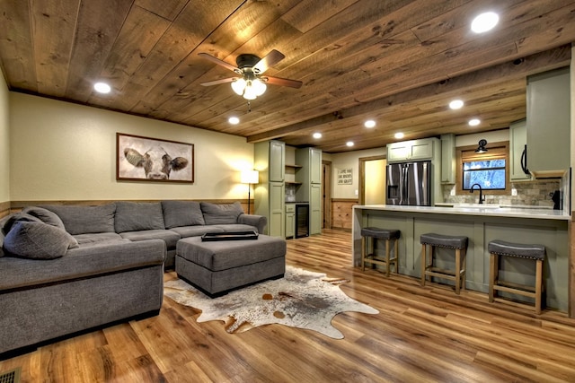 living room featuring sink, wood ceiling, ceiling fan, light hardwood / wood-style floors, and beverage cooler