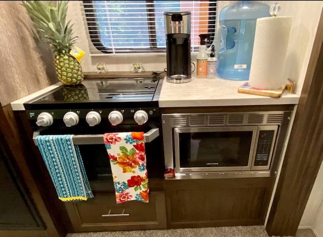 details featuring electric stove, stainless steel microwave, and carpet