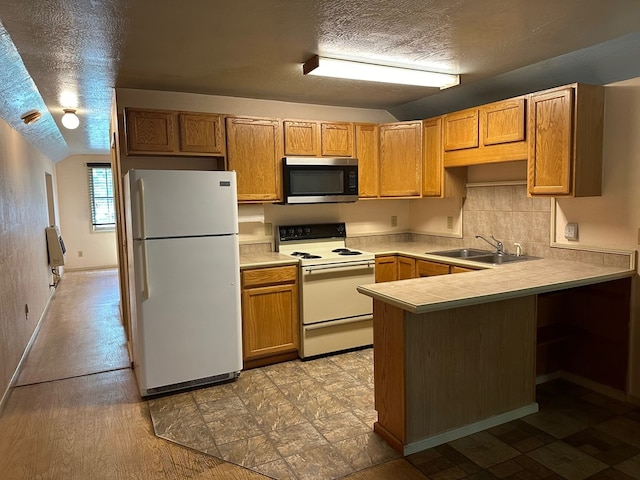 kitchen with a textured ceiling, sink, lofted ceiling, kitchen peninsula, and white appliances